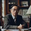 资深记者何浩然，眼镜男性，坐于编辑室内，专注于法律税务类明星黑料的深度调查